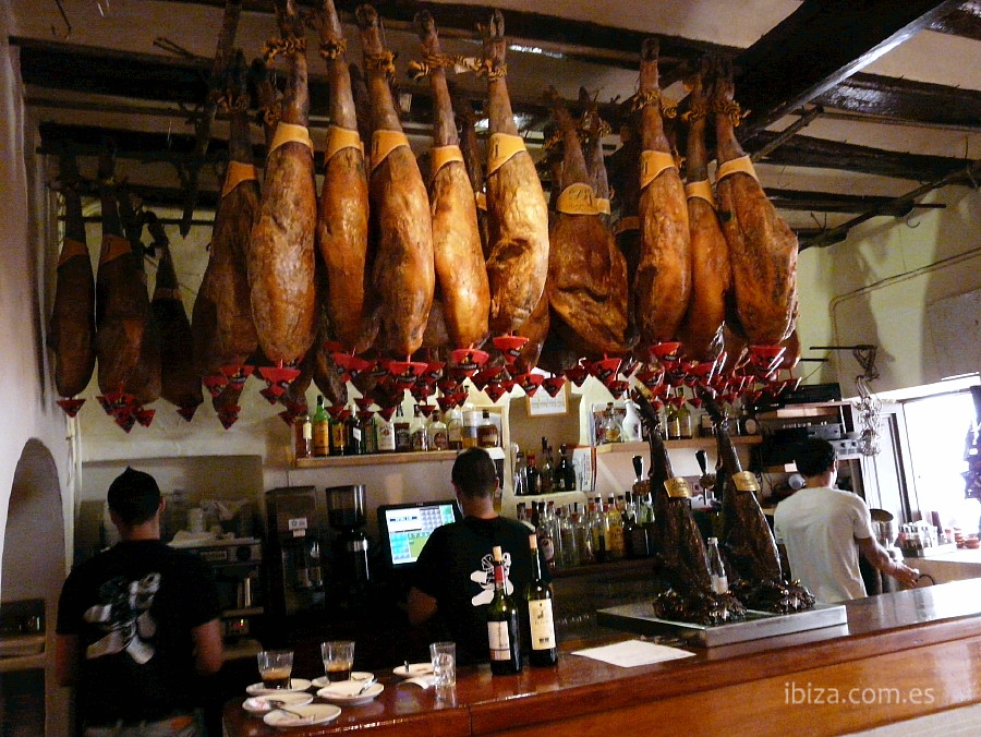 Jamones típicos españoles colgando sobre la barra del Bar Costa de Santa Gertrudis