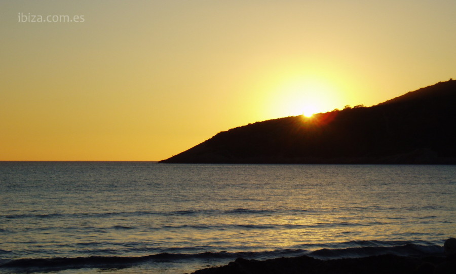 El sol se pone tras el monte desde la playa de Las Salinas